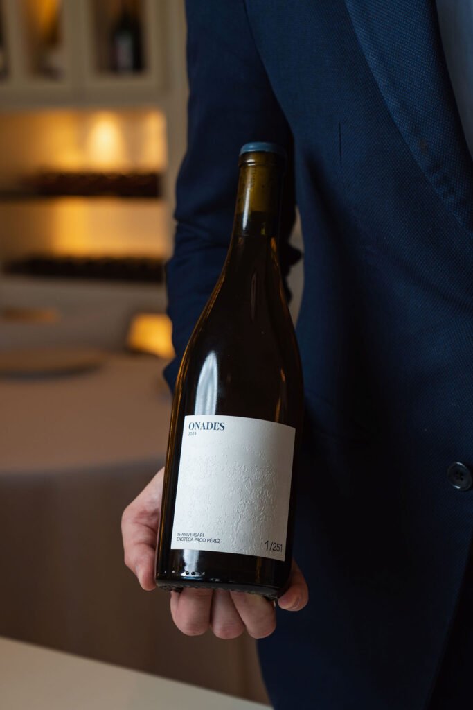 Camarero de Enoteca Paco Pérez sirviendo vino Onades con etiqueta homenaje al mar